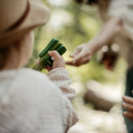 Franziska Näther reicht einem Kind ein Musikinstrument: Glückliche Kinder erleben Waldmusikpädagogik in der freien Natur in Göttingen
